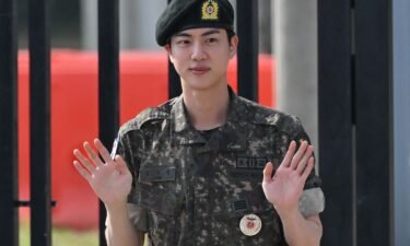K-pop boy band BTS member Jin waves after being discharged from his mandatory military service outside a military base in Yeoncheon