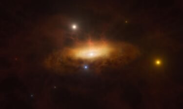 An artist's illustration shows a massive black hole as it wakes up at the center of a distant galaxy. The black hole pulls in a growing disk of material as it feeds on surrounding gas