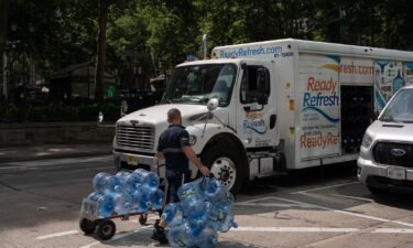 A worker wheels empty water jugs to a truck during high temperatures in New York on June 20.
