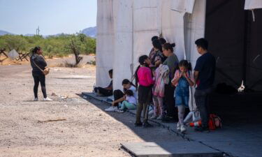 People wait to be taken in by Border Patrol after crossing the US-Mexico border near the San Miguel gate on the Tohono O'odham reservation