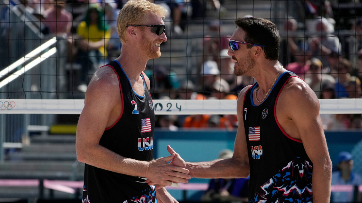 Miles Evans and Chase Budinger celebrate defeating France in a beach volleyball match during the Paris Olympic Games at Eiffel Tower Stadium.