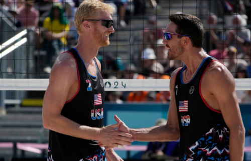 Miles Evans and Chase Budinger celebrate defeating France in a beach volleyball match during the Paris Olympic Games at Eiffel Tower Stadium.
