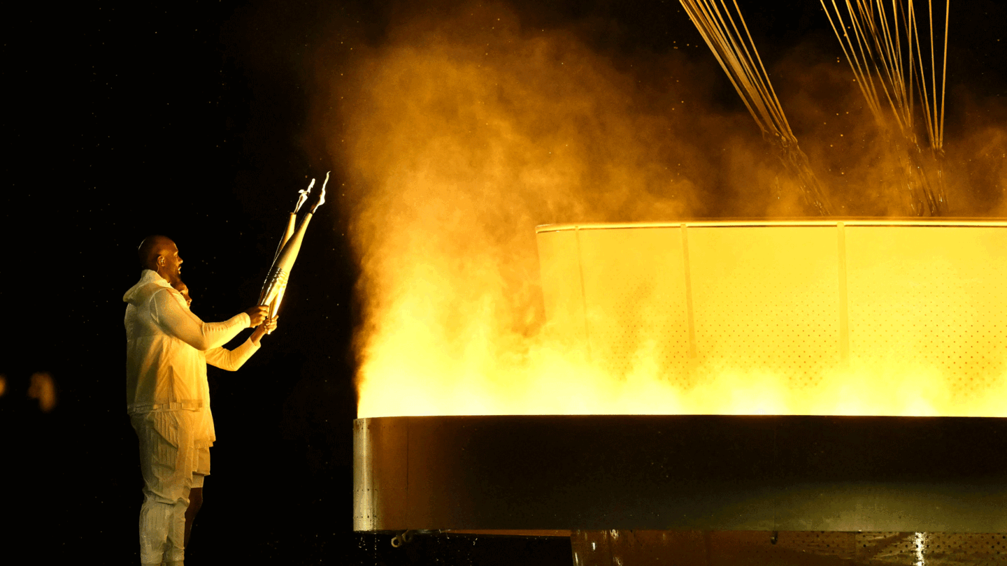 France's torchbearers judoka Teddy Riner and sprinter Marie-Jo Perec light the Olympic cauldron