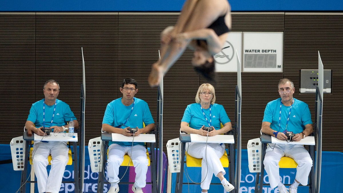 Judges look on as a diver descends in front of them.