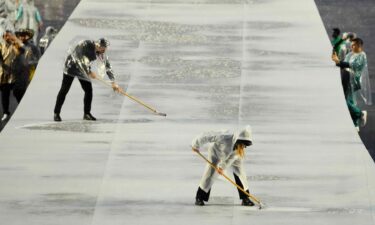 A worker dries the stage in the Trocadero as rain falls during the Opening Ceremony for the Paris 2024 Olympics.