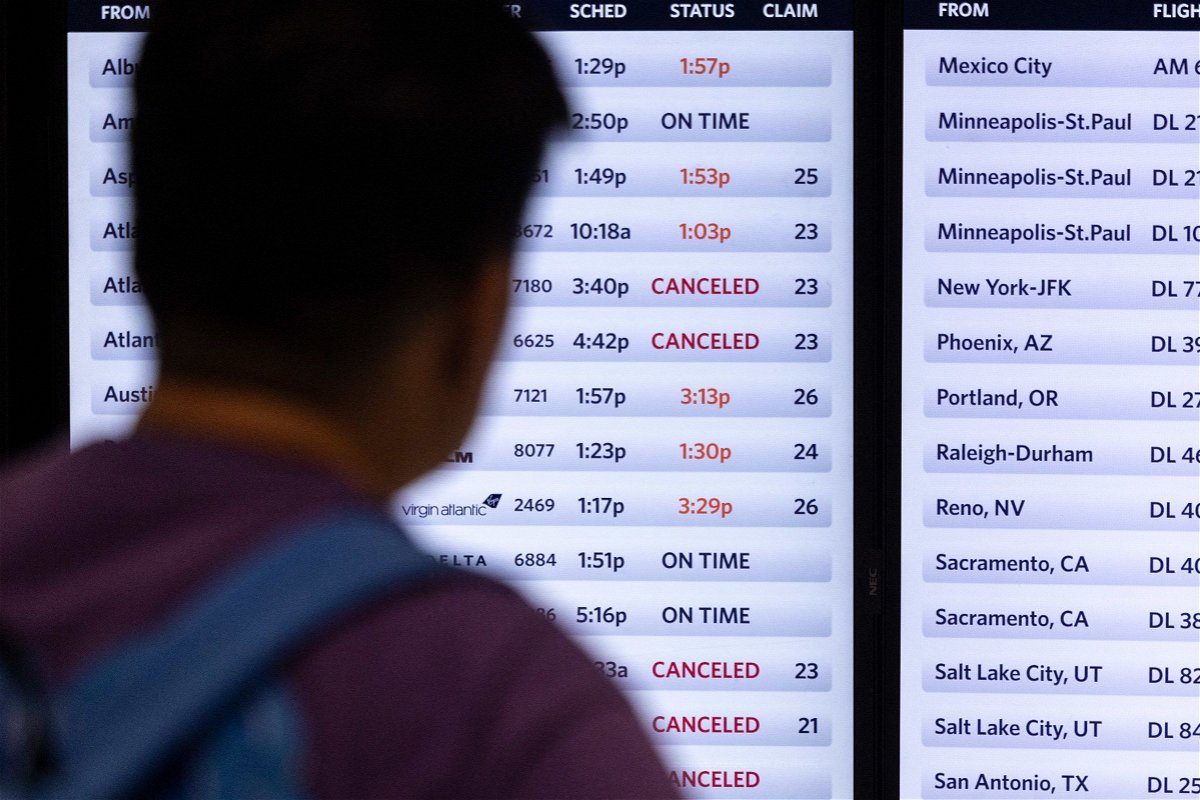 <i>Etienne Laurent/AFP/Getty Images via CNN Newsource</i><br/>A traveler looks at a screen displaying delayed and canceled flights in Terminal 2