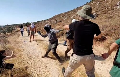 Masked Israeli settlers and Palestinian farmers and foreign activists clash in the West Bank town of Qusra on July 21