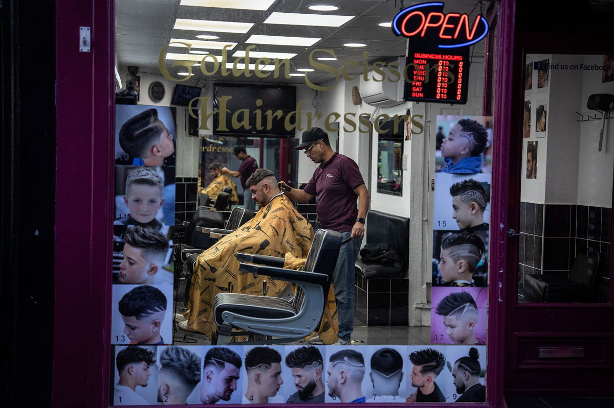 <i>Carl Court/Getty Images via CNN Newsource</i><br/>A man gets his hair cut in a barber shop in Colchester
