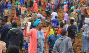 A woman cries as hundreds of people gather at the site of a mudslide.