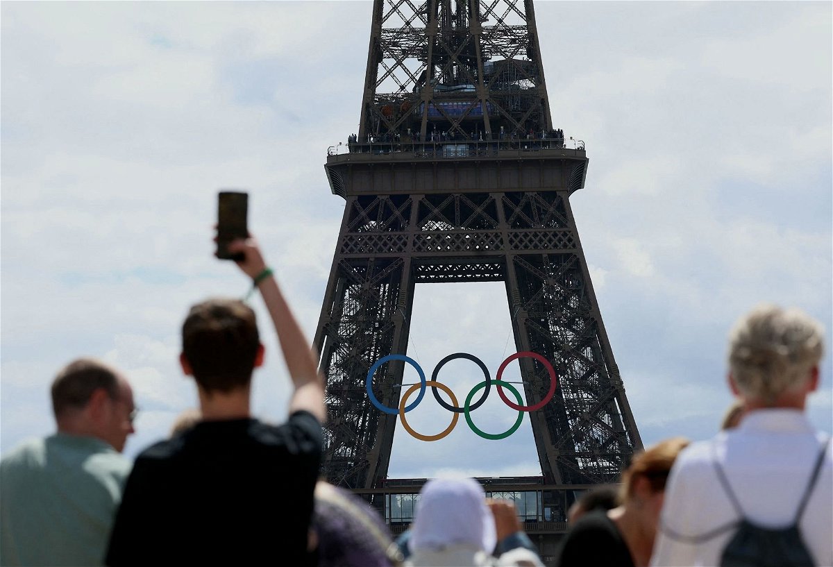 <i>Emmanuel Dunand/AFP/Getty Images via CNN Newsource</i><br/>Visitors look at The Eiffel Tower adorned with The Olympic Rings ahead of the 2024 Olympic Games in Paris on July 16.
