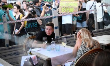 Diners cower as protesters march past a restaurant.