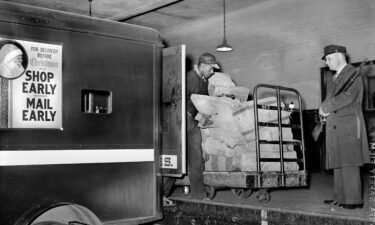 Workers on loading platform putting mail on trucks in 1938.