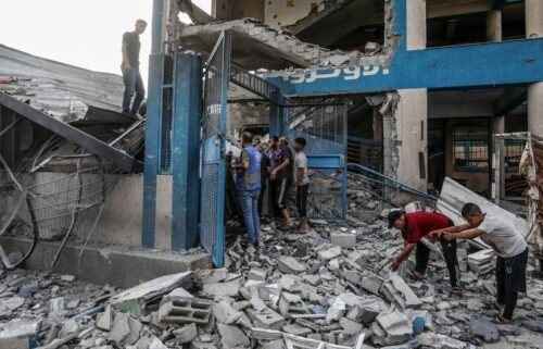 Palestinians and UN workers examine the destroyed UNRWA school in Nuseirat refugee camp of Deir al-Balah