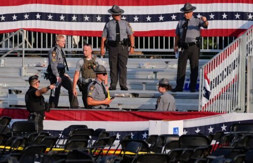 Law enforcement officers work at the campaign rally site for Republican presidential candidate former President Donald Trump is empty and littered with debris July 13