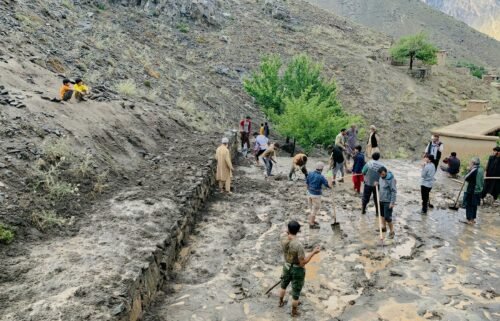 Afghan residents shovel mud following flash floods after heavy rainfall at Pesgaran village in Dara district