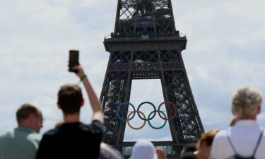 Visitors look at the Eiffel Tower adorned with the Olympic Rings ahead of the Olympic Games in Paris.