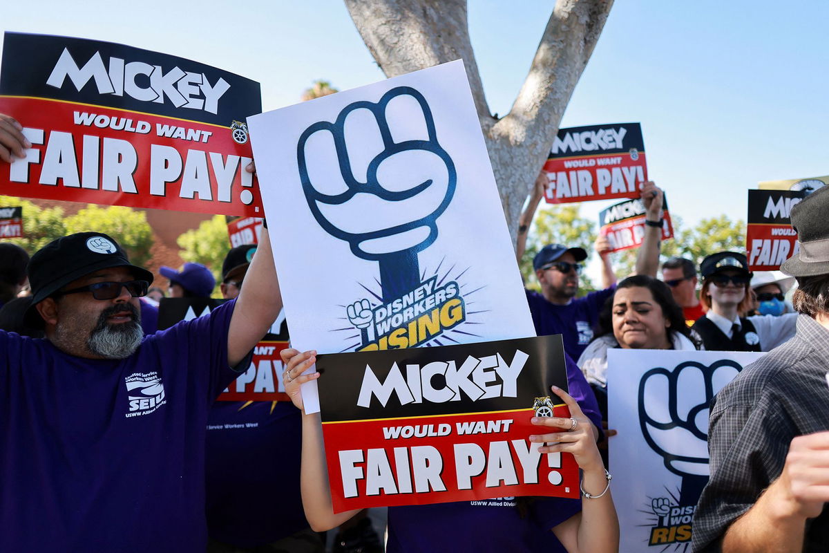 <i>David Swanson/Reuters via CNN Newsource</i><br/>Workers gather with signs as the Teamsters union and Disney cast members demand fair wages at a rally outside Disneyland