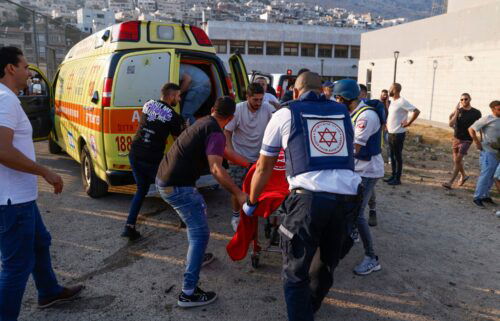Israeli security forces and medics transport casualties along with local residents