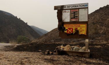 A burned visitor information sign from the Durkee Fire is pictured amid charred hillside near Huntington, Oregon