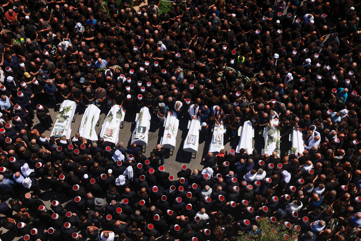 <i>Menahem Kahana/AFP/Getty Images via CNN Newsource</i><br/>Druze elders and mourners surround the coffins of 10 of the children killed during the strike on July 27.