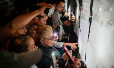 Voters look at electoral lists prior to the opening of the polls for presidential elections in Caracas