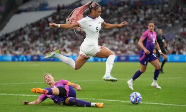 Trinity Rodman (center) of the United States jumps over the tackle of Alexandra Popp (left) of Germany during the Paris Olympics 2024.