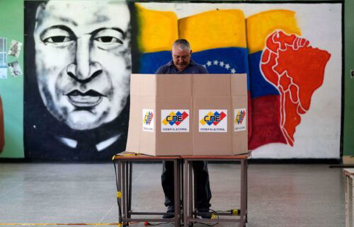 A voter chooses his candidate in front of a mural of late Venezuelan President Hugo Chavez during the presidential election in Caracas