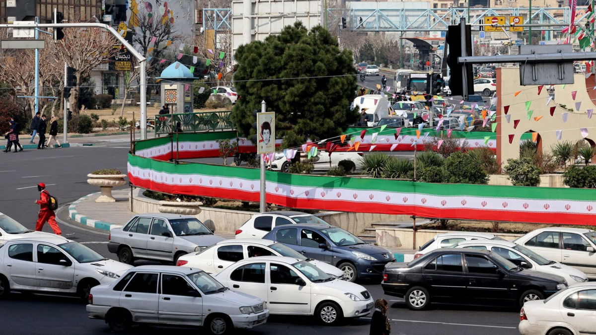 <i>Atta Kenare/AFP/Getty Images via CNN Newsource</i><br/>Cars drive past a wall covered by a banner in the colours of the national flag in Tehran