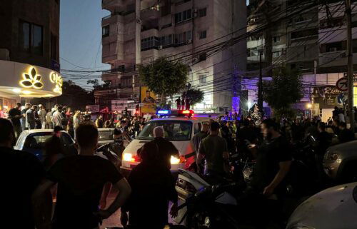 People gather near a site hit by what security sources said was a strike on the southern suburbs of Beirut