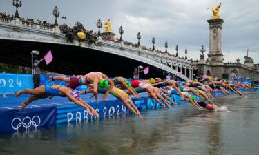 Athletes dive into the water for the start of the women's individual triathlon competition on July 31 in Paris.