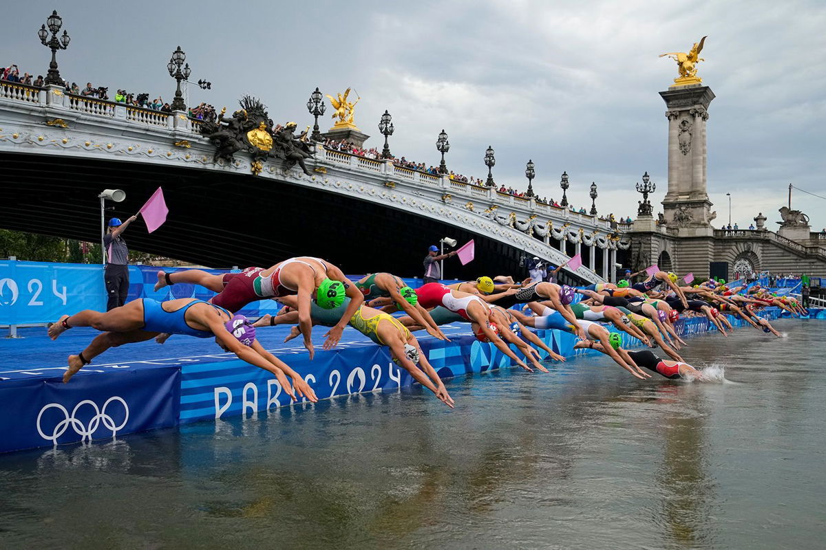 <i>Vadim Ghirda/AP via CNN Newsource</i><br/>Athletes dive into the water for the start of the women's individual triathlon competition on July 31 in Paris.