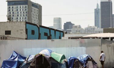 A person stands near an encampment of homeless people in the Skid Row community on July 25