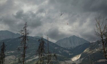 A helicopter buckets water onto smouldering fires outside of Jasper