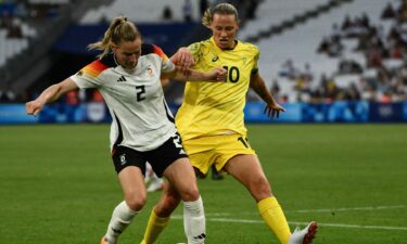 Two soccer athletes contest for the ball.