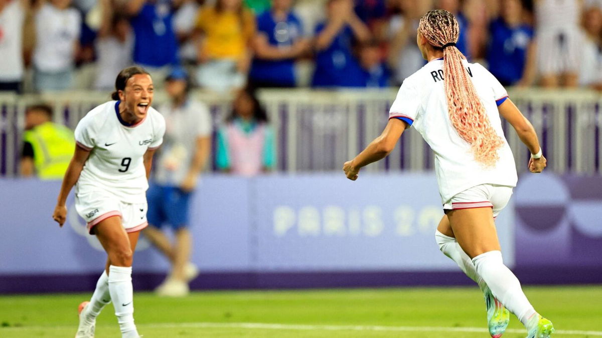 USWNT players celebrate after scoring a goal.