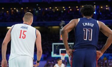 Nikola Jokic stands next to Joel Embiid