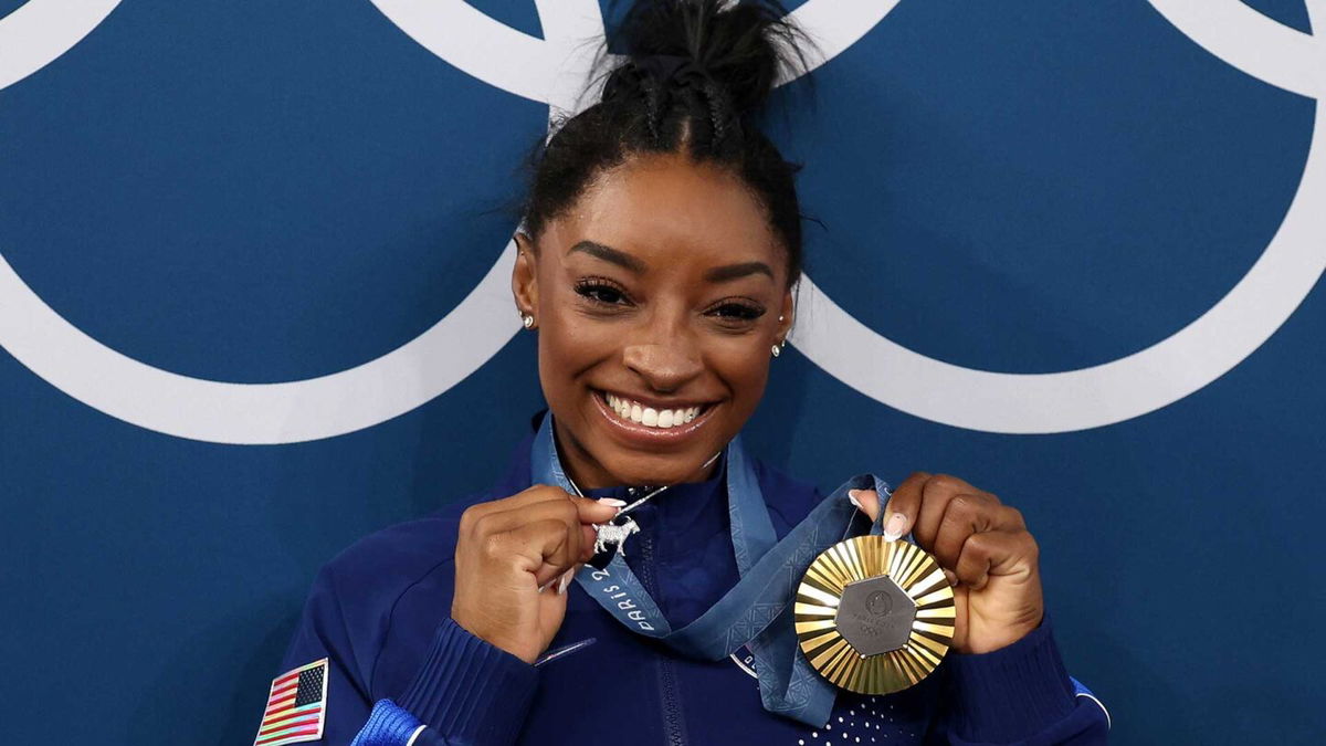 Simone Biles poses with her all-around Olympic gold medal and goat charm necklace at the 2024 Paris Olympics.