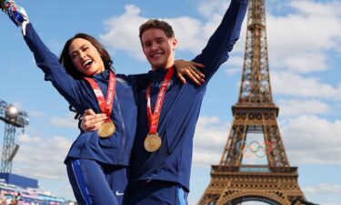 Madison Chock and Evan Bates pose in front of the Eiffel Tower after receiving their gold medals.