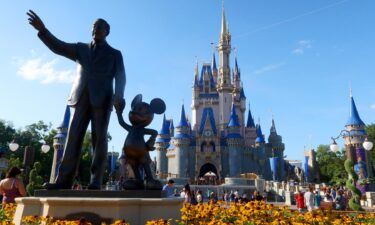 A statue of Walt Disney and Mickey Mouse stands in a garden in front of Cinderella's Castle at the Magic Kingdom Park at Walt Disney World.