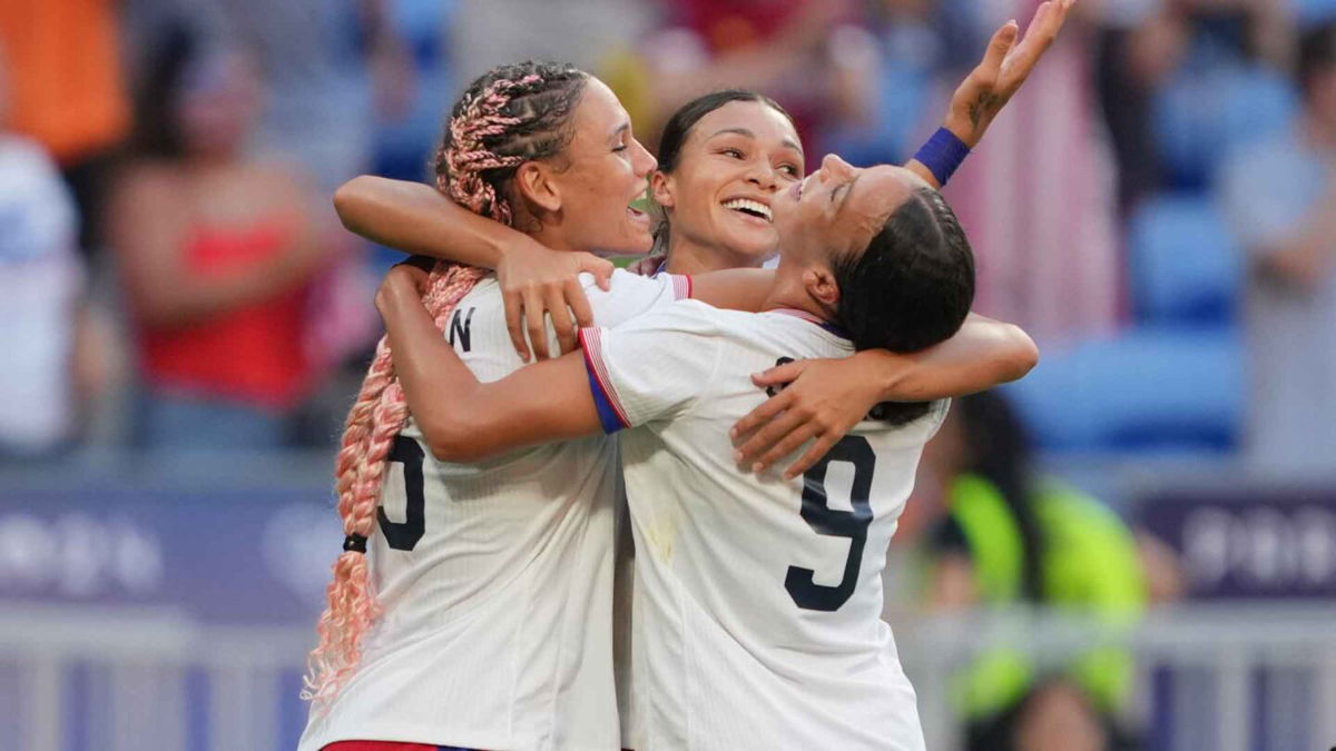 USWNT players celebrate after scoring a goal.