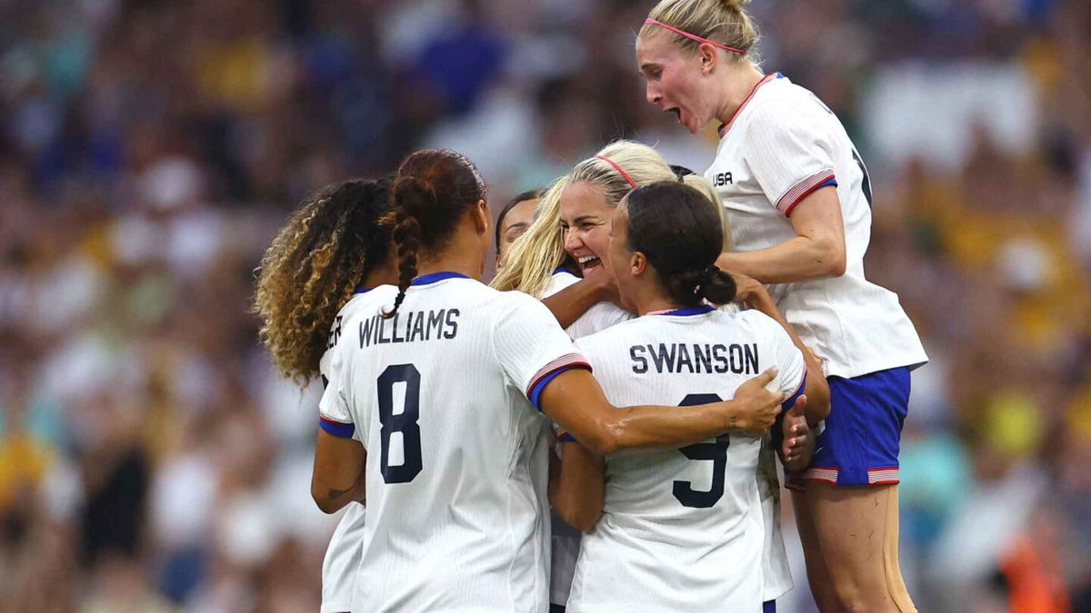 USWNT players celebrate after scoring a goal.