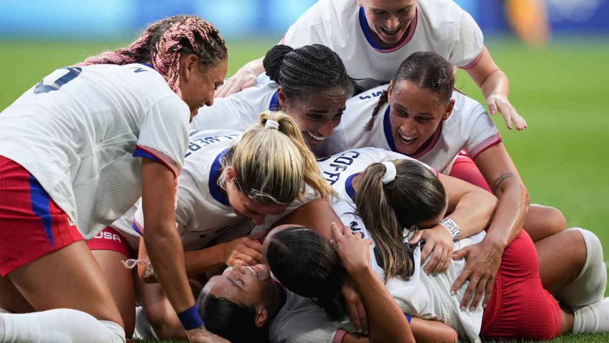 USWNT players celebrate after scoring a goal.