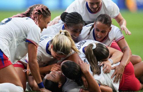 USWNT players celebrate after scoring a goal.