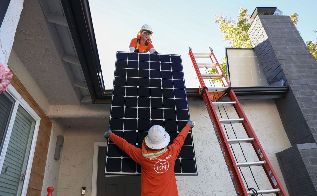 <i>Sandy Huffaker/Bloomberg/Getty Images via CNN Newsource</i><br/>Workers install solar panels on the roof of a home in Poway