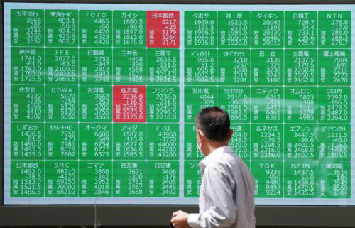 A man looks at an electronic board displaying stock prices in Tokyo on August 2.