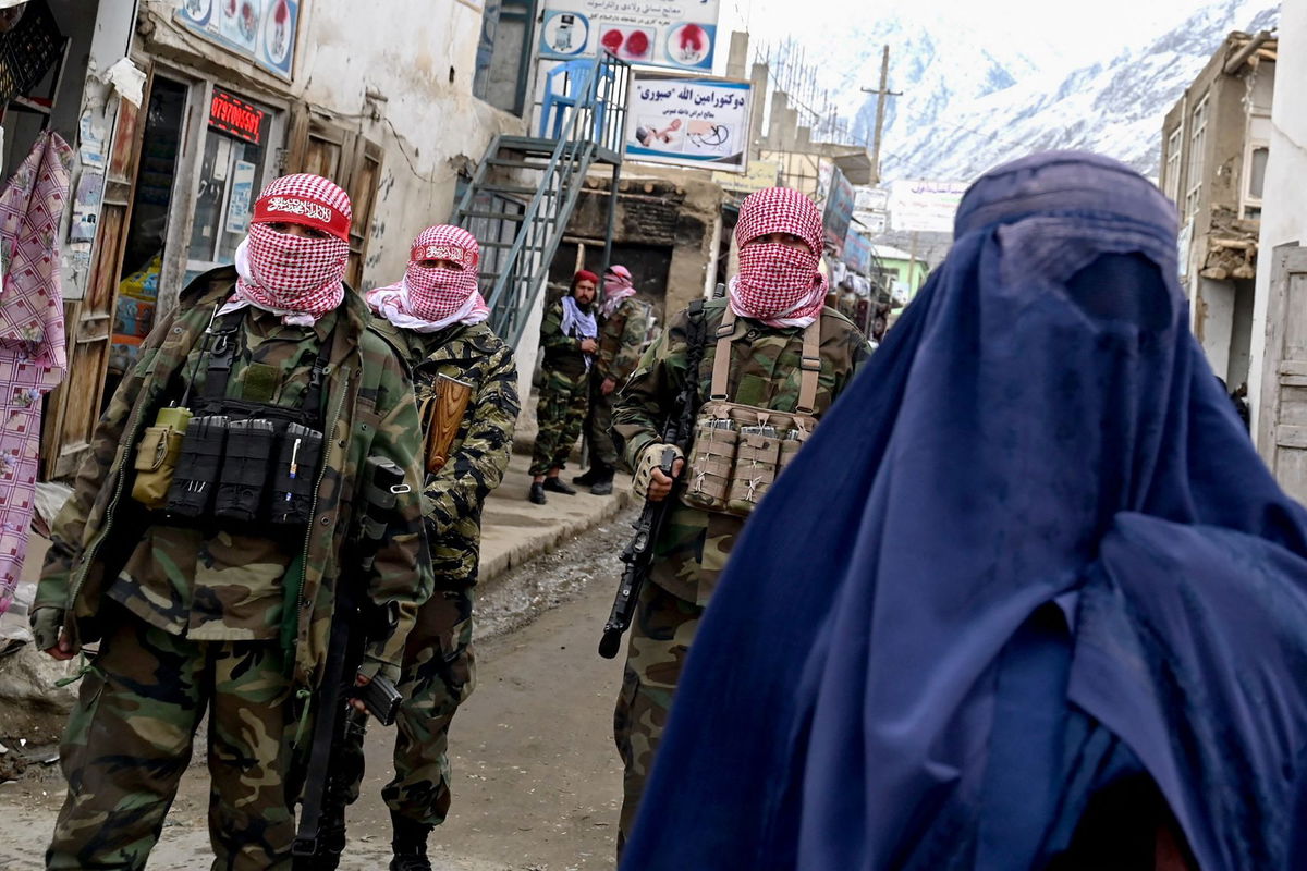 <i>Wakil Kohsar/AFP/Getty Images via CNN Newsource</i><br/>Taliban guards stand beside a burqa-clad woman on a street at a market in the Baharak district of Badakhshan province