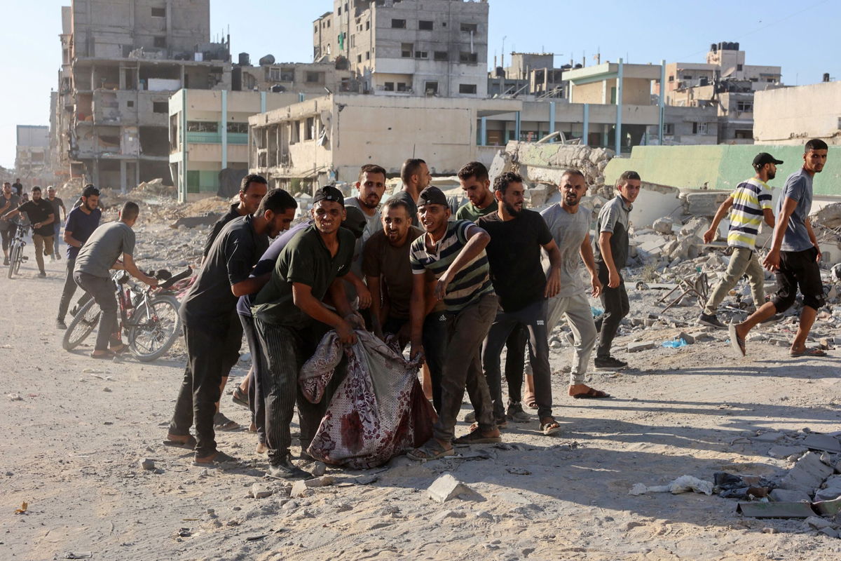 <i>Omar Al-Qattaa/AFP/Getty Images via CNN Newsource</i><br/>Palestinians evacuate a body pulled from the rubble following Israeli bombardment which hit a school complex