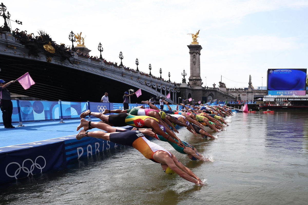 <i>Anne-Christine Poujoulat/AFP/Getty Images via CNN Newsource</i><br/>Athletes dive into the River Seine to start the swimming stage of the men's individual triathlon at the Paris 2024 Olympic Games on July 31.