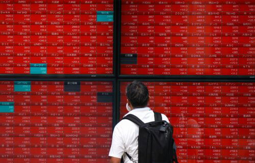 A man looks at an electronic quotation board displaying stock prices of the Nikkei 225 on the Tokyo Stock Exchange in Tokyo on August 6