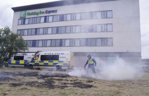 A police officer extinguishes a fire after a riot outside the Holiday Inn Express in Rotherham